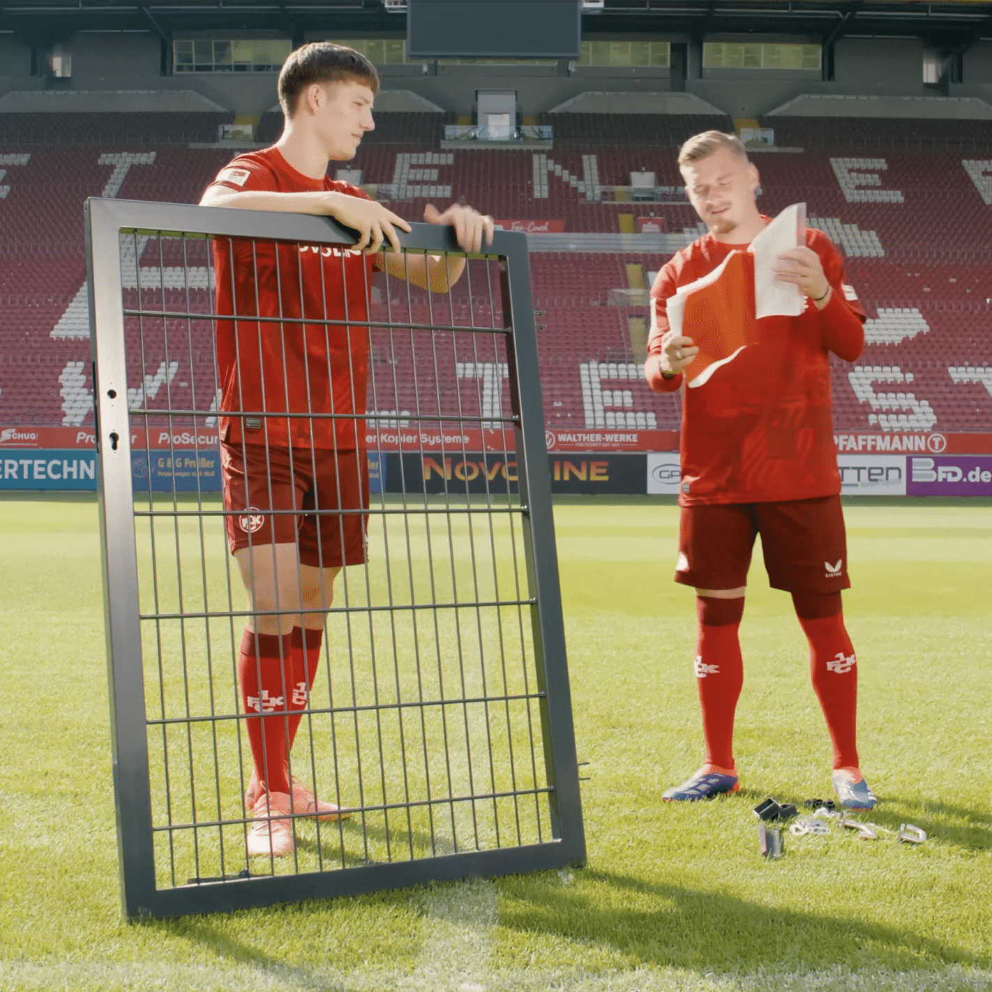 Zwei Fußballspieler bauen ein Zauntor auf